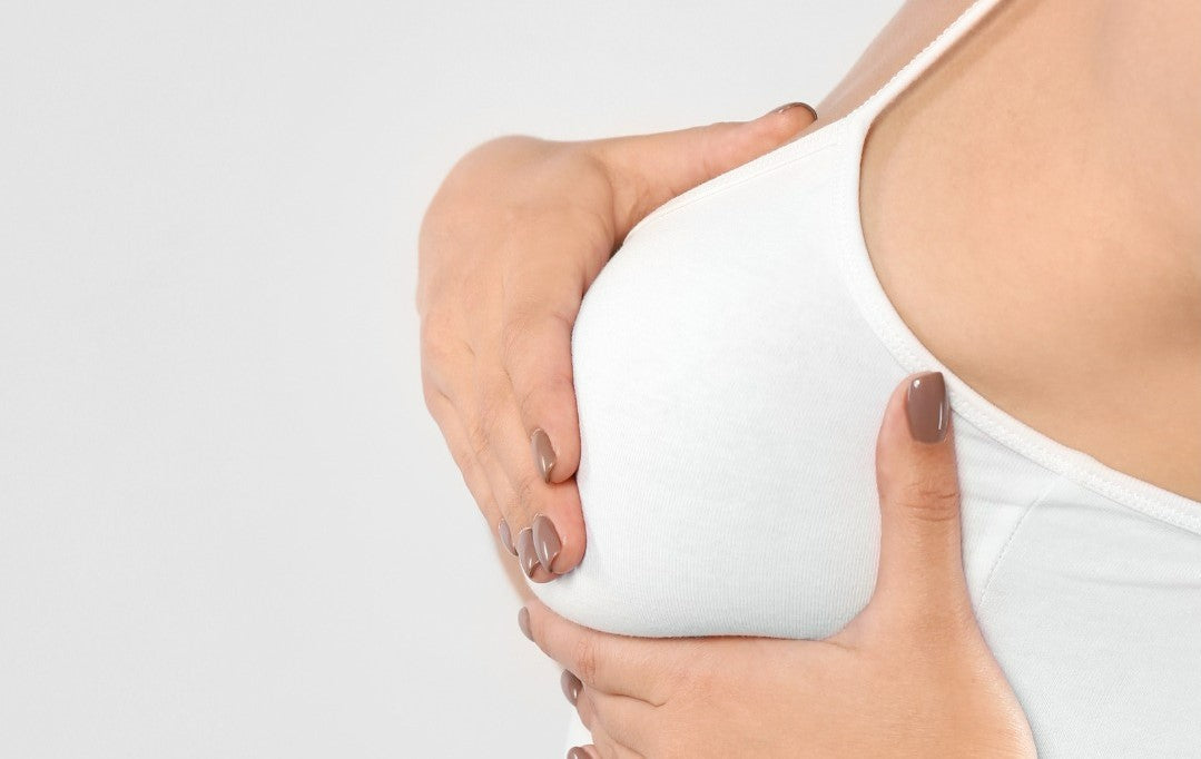 woman wearing a white bra and feeling her breast from breast pumping soreness