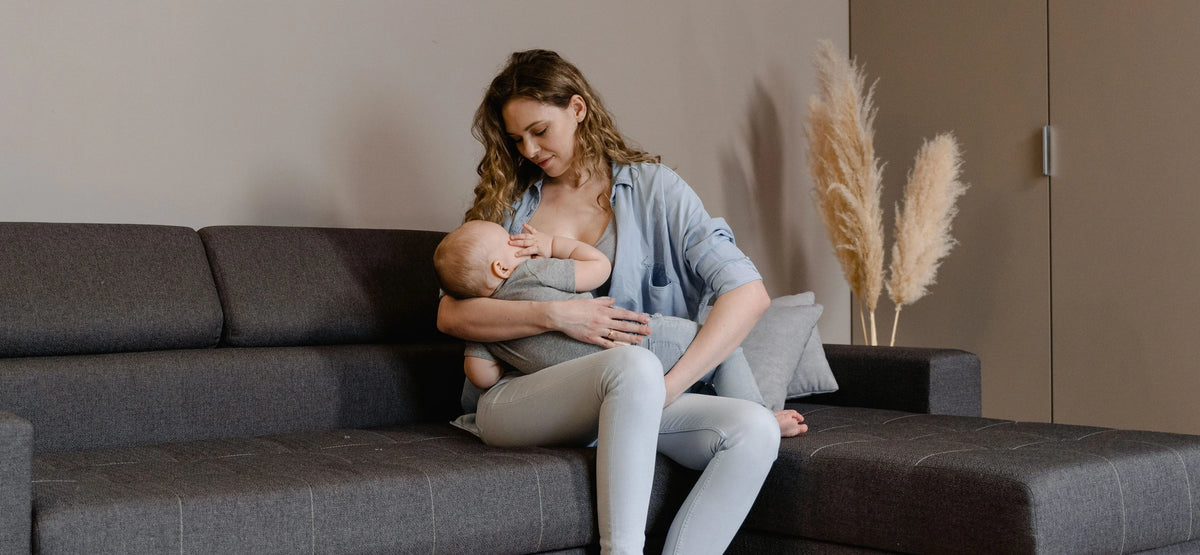 Mom breastfeeding her baby while sitting on the couch
