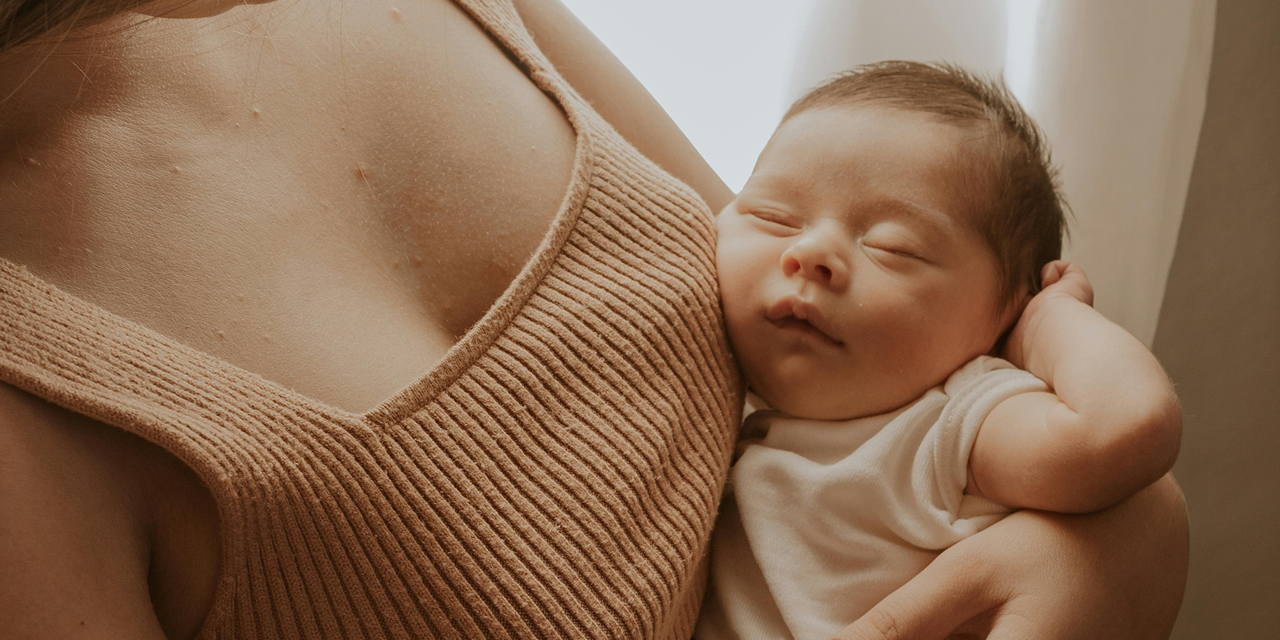 mother holding baby in her arms while baby is asleep