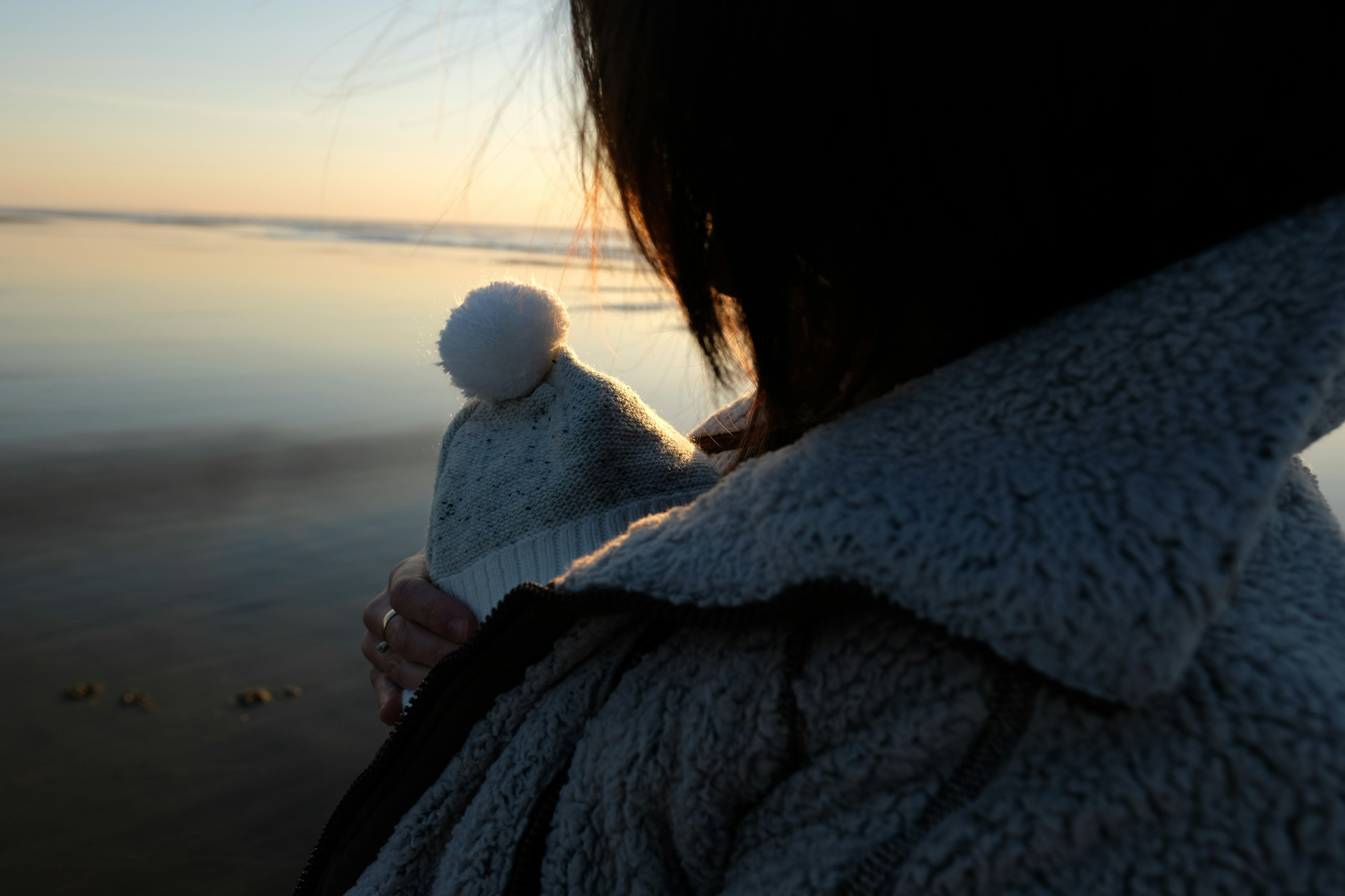 woman out at the beach with her baby while watching the sunset