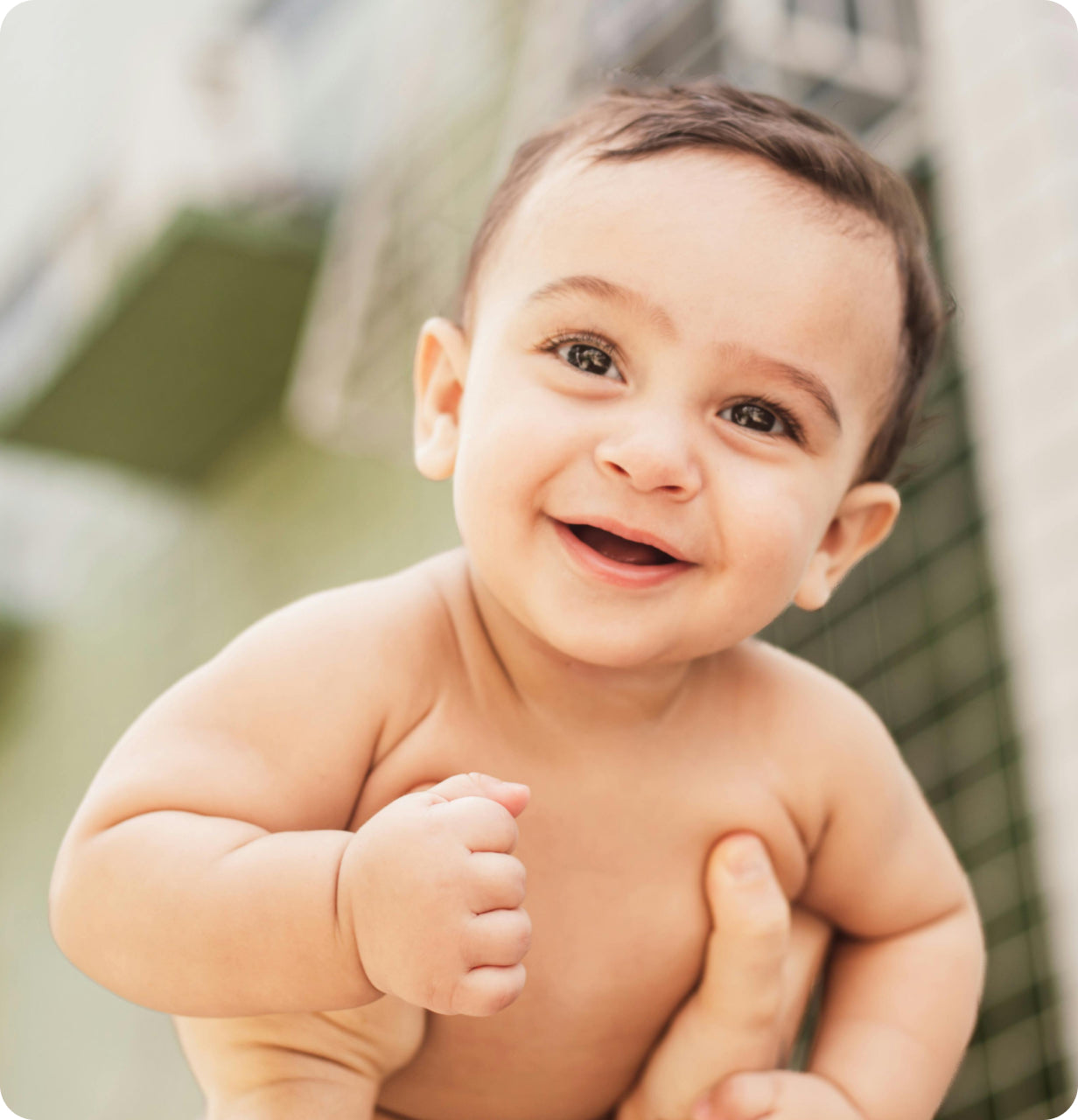 happy baby boy smiling while being lifted up by a parent