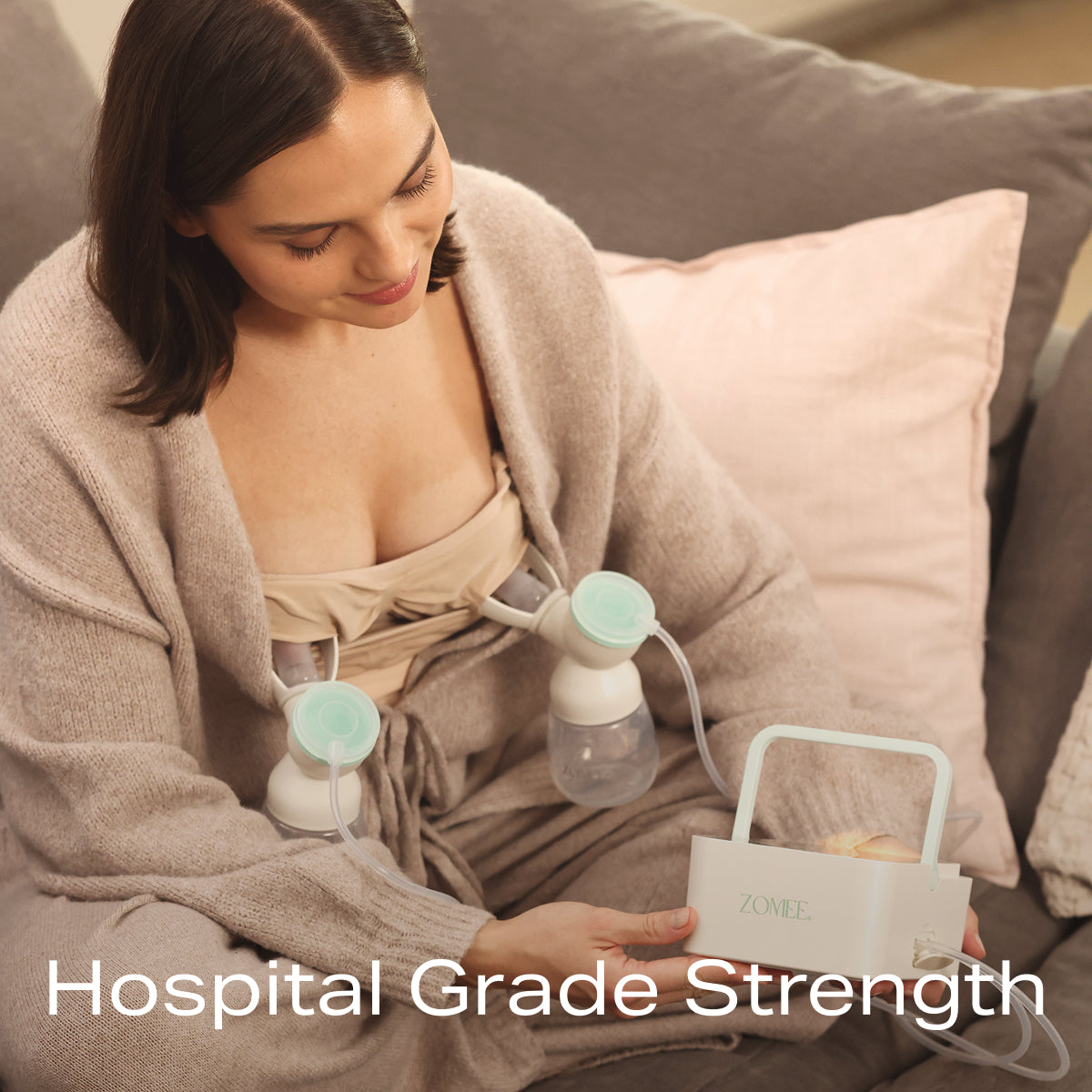 Mom sitting on the couch using the Mother's Nature H1 Breast Pump